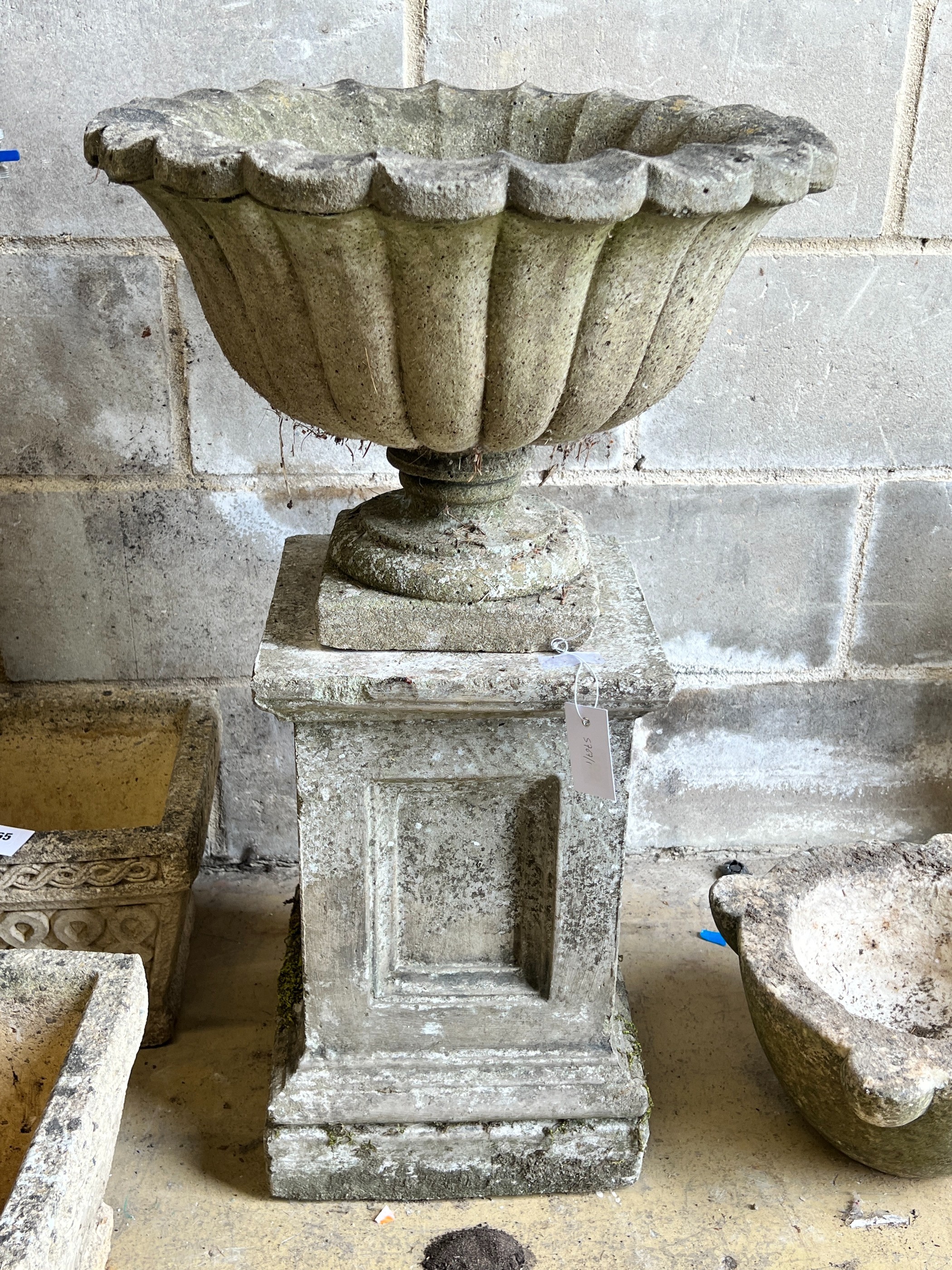 A reconstituted stone campana garden urn on square plinth, diameter 49cm, height 82cm